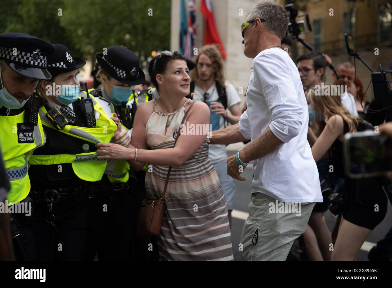 London, UK. 14th June 2021. Anti-vaxx protester trys to stop the Met Police from pushing forward outside Downing Street. Yuen Ching Ng/Alamy Live News. Stock Photo