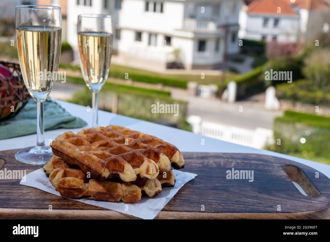 Breakfast with fresh baked belgian waffles and brut champagne sparkling wine in flute glasses served on outdoor cafe or bistro terrace in France Stock Photo