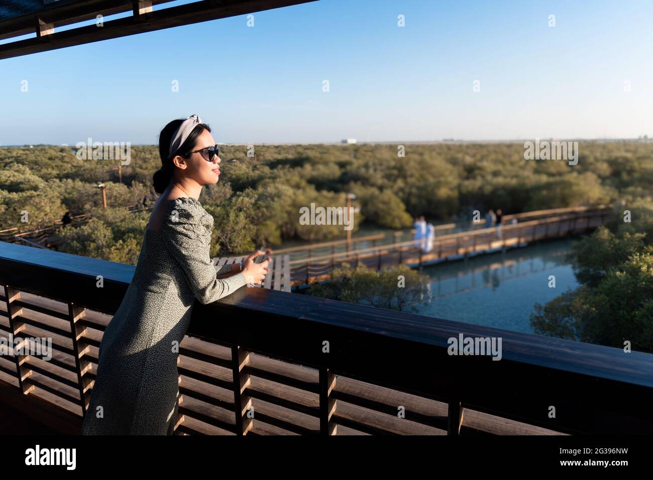 Asian female tourist visiting Mangrove walk seaside promenade public park in Jubail island Abu Dhabi the capital city of United Arab Emirates Stock Photo