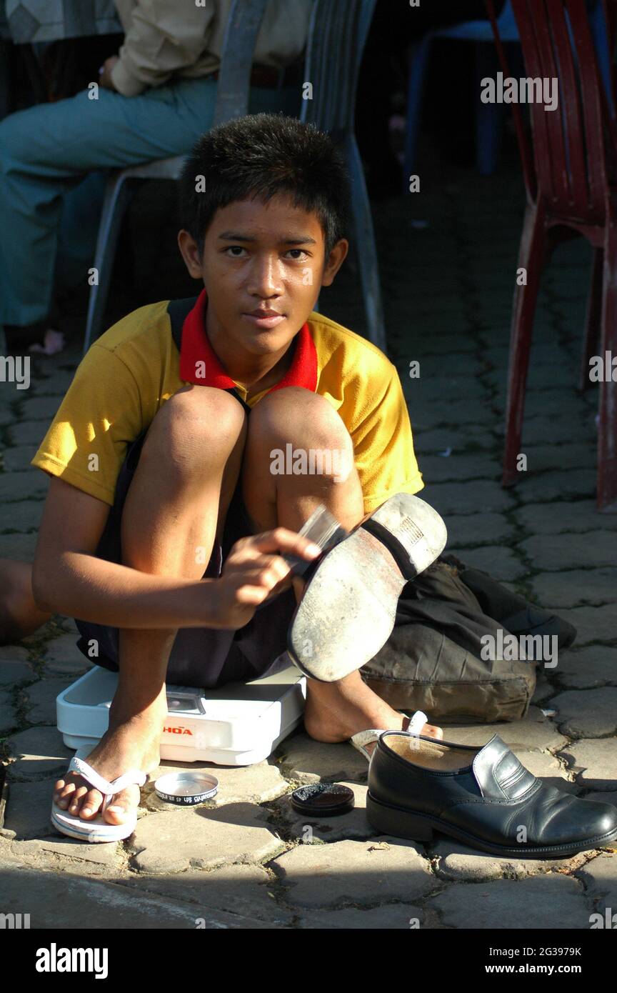 A boy polishing shoes, at a pavement, in the city of Phnom Penh. Usually  children from poorer community walk around the city to earn a living by  offering shoe polishing service. Phnom
