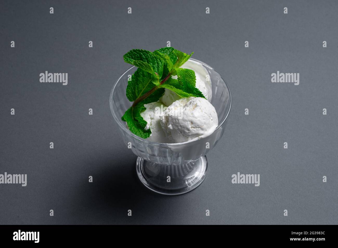 tasty vanilla ice cream with fresh mint in glass bowl on black ...