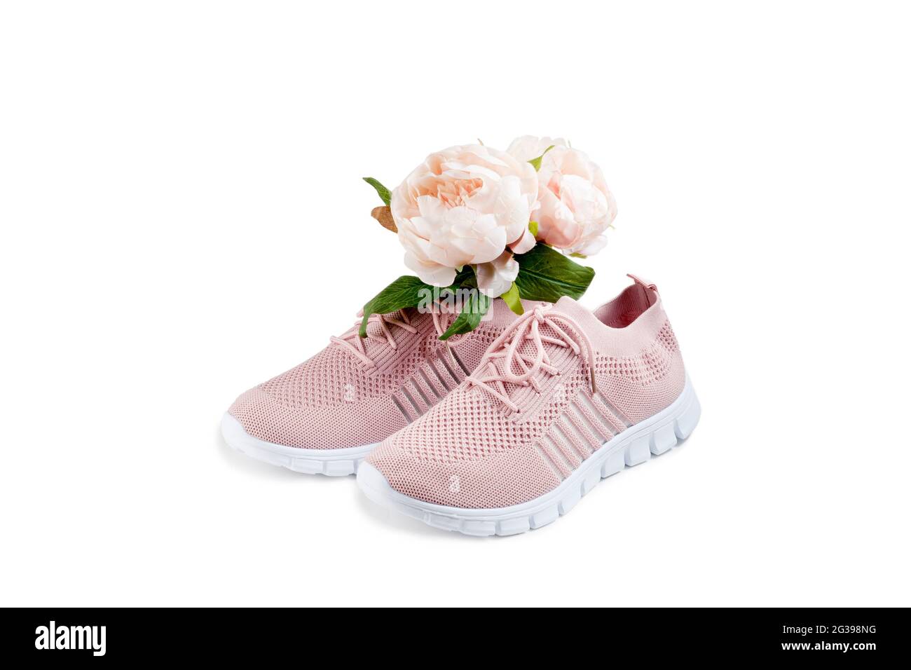 Pink women's shoes from a light soft fabric on a white background. There is a bouquet of flowers inside the shoe. Stock Photo
