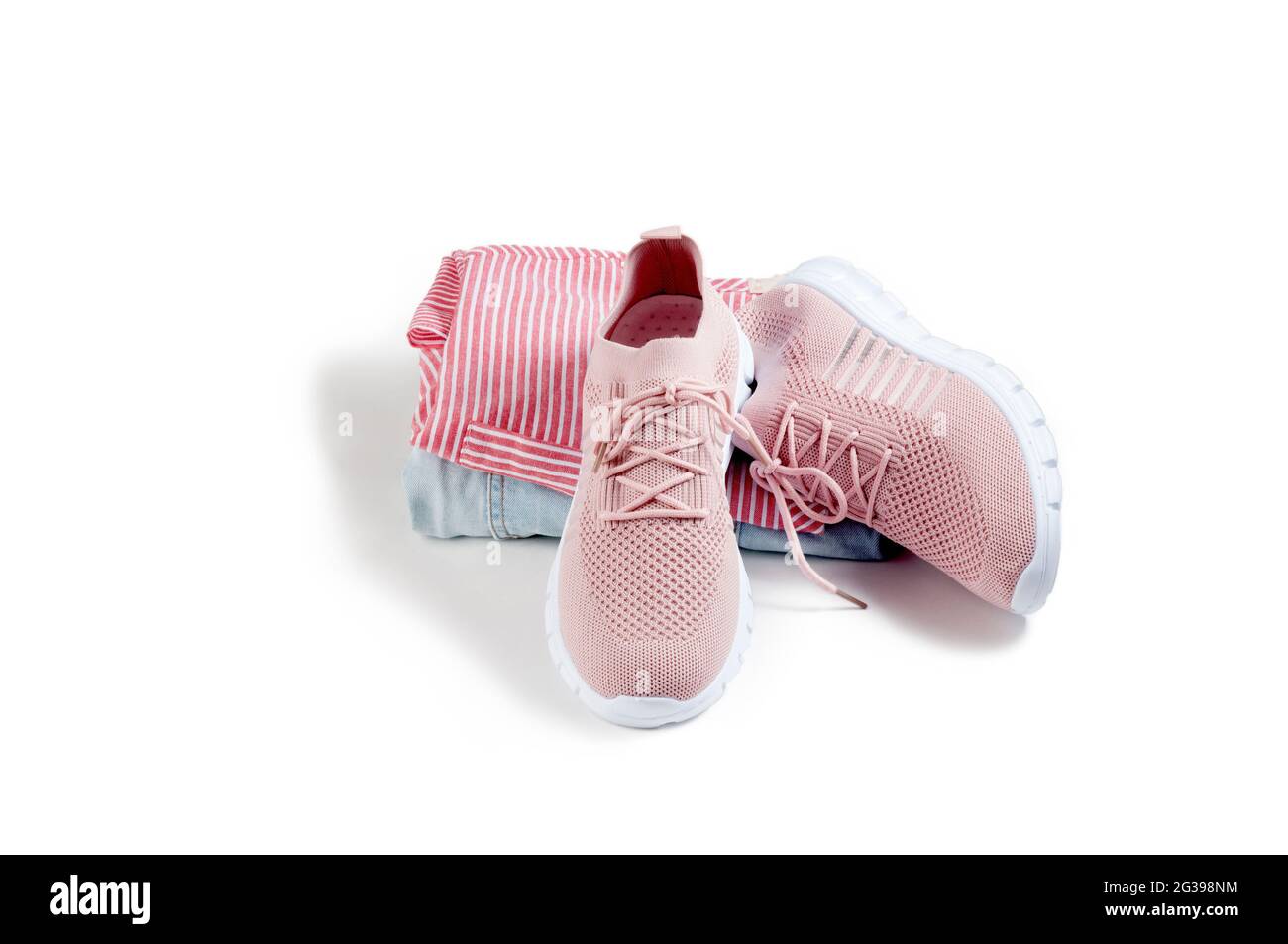 Pink women's shoes from a light soft fabric lying on a white background with a shirt and trousers. Stock Photo