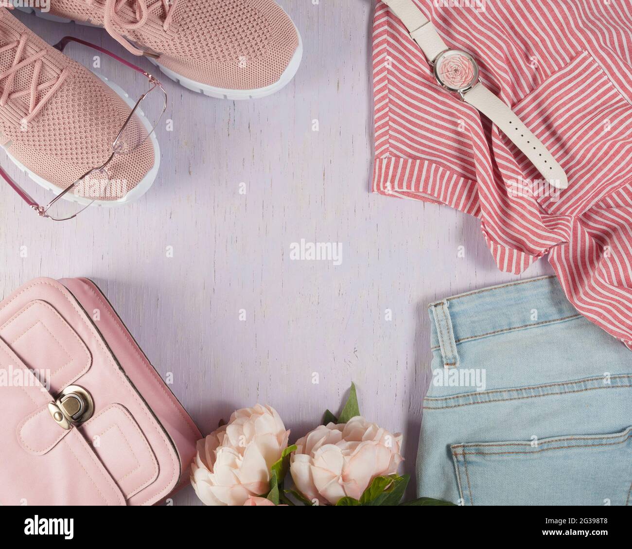 Things are laid out on a lilac, wooden background. Small pink handbag ...