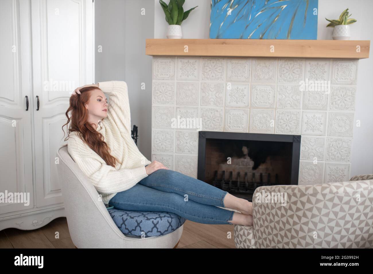Pretty woman having rest at home near fireplace Stock Photo