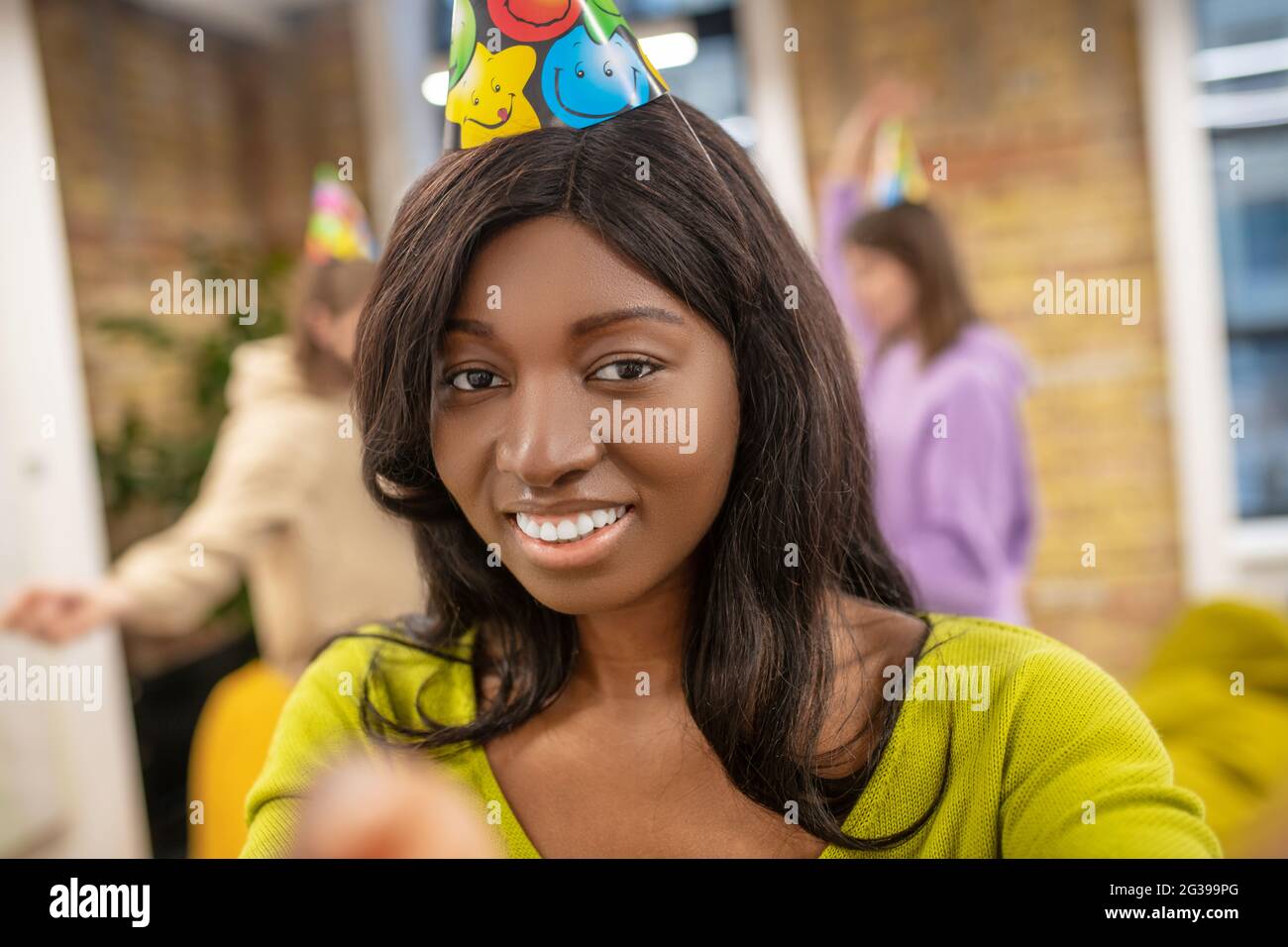 African American girl with toothy smile in party hat Stock Photo
