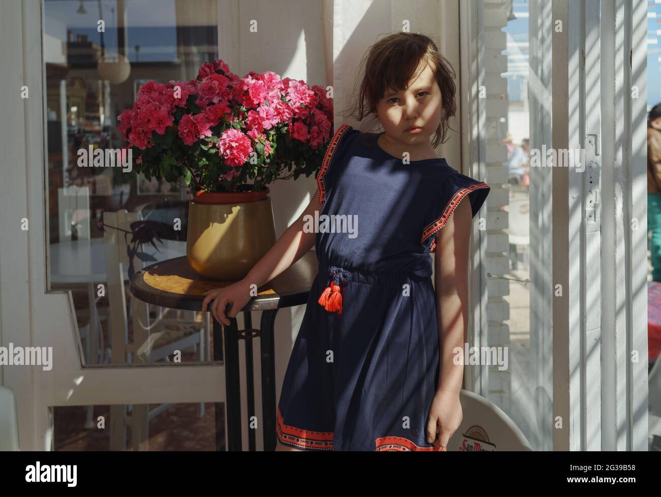 Little girl standing among domestic flower Stock Photo