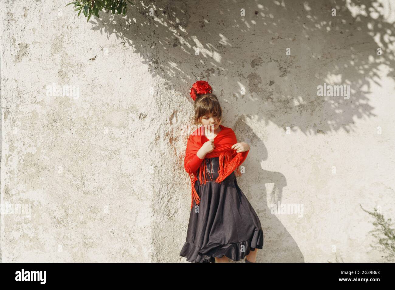 Little girl standing against white wall Stock Photo