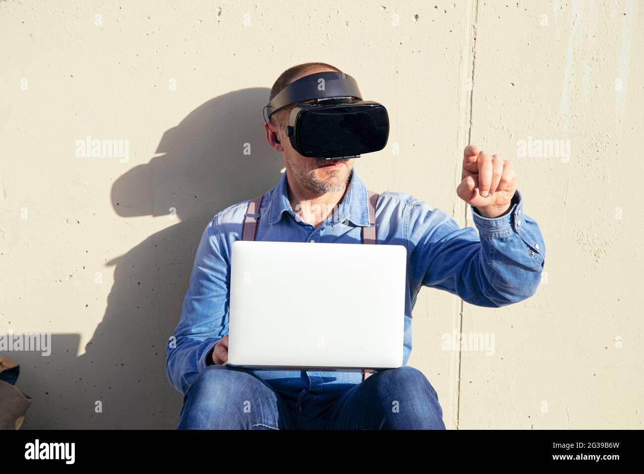 Businessman examining virtual reality simulator while using laptop Stock Photo