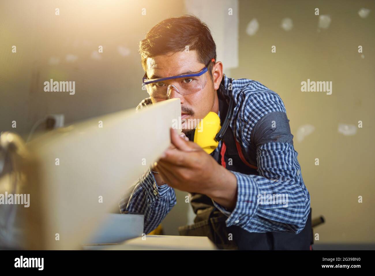 Selective focus of handsome man in goggles and apron in workshop Stock Photo