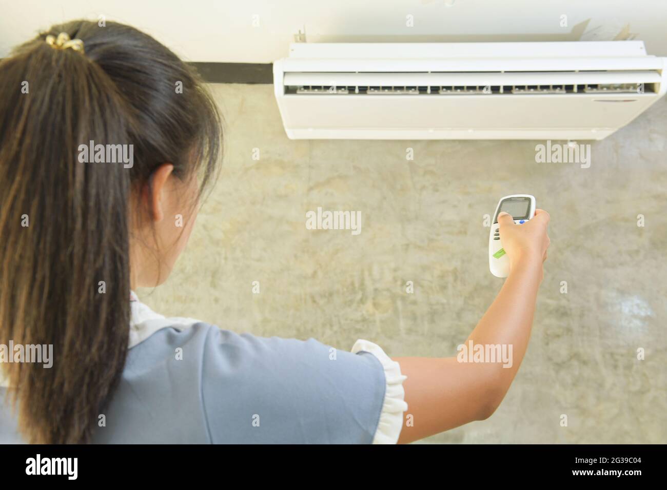 Hand with remote control directed on air conditioner Stock Photo