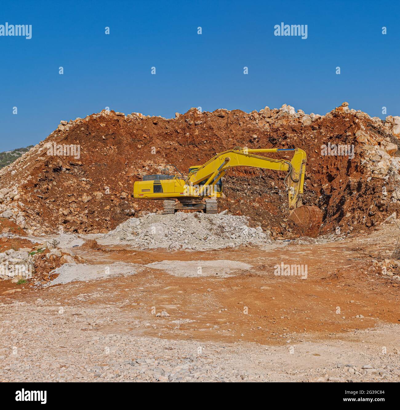 Yellow excavator at a road construction site Stock Photo