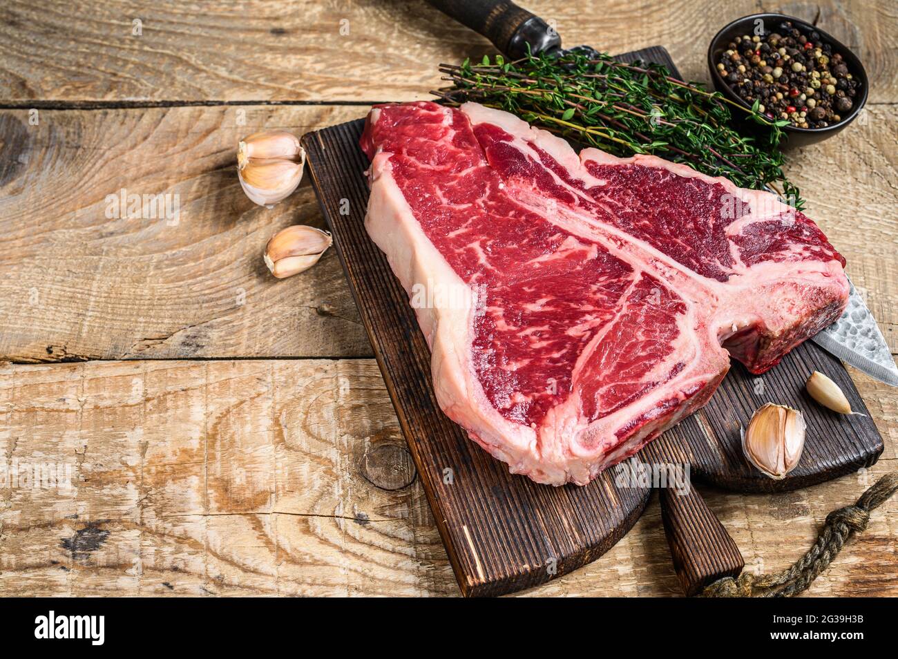 https://c8.alamy.com/comp/2G39H3B/raw-porterhouse-or-t-bone-beef-meat-steak-with-herbs-on-a-wooden-cutting-board-wooden-background-top-view-copy-space-2G39H3B.jpg