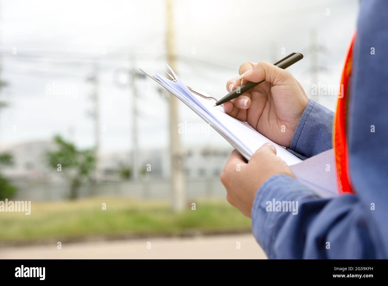 Hand holding clipboard and write on document checklist high voltage system, Working woman Stock Photo