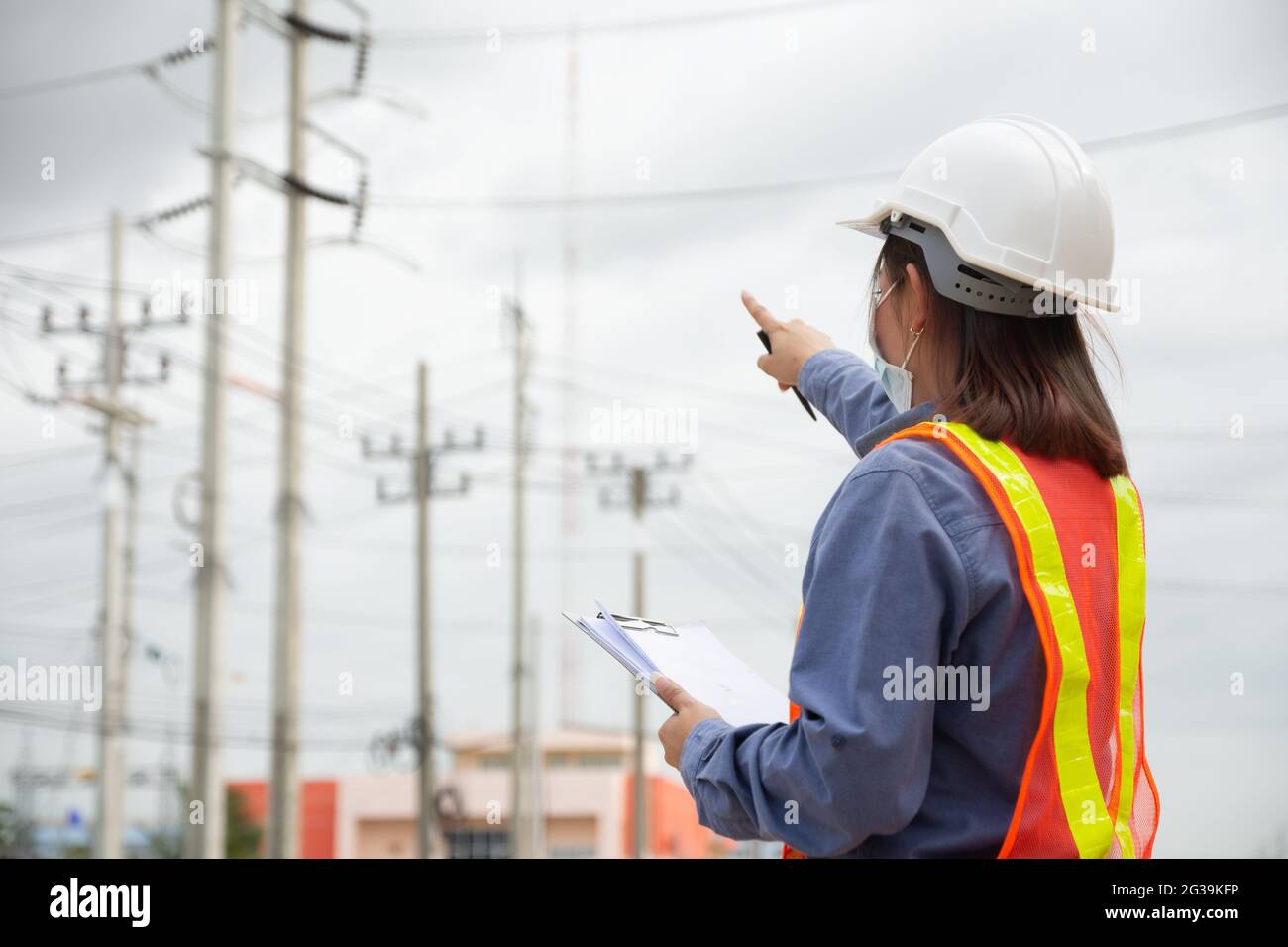 Hand holding clipboard and write on document checklist high voltage system, Working woman Stock Photo