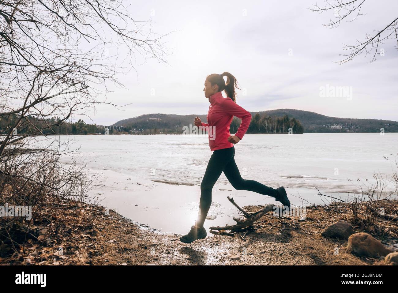 Spring running girl training outside jogging by the lake in nature countryside. Woman athlete runner exercising cardio Stock Photo