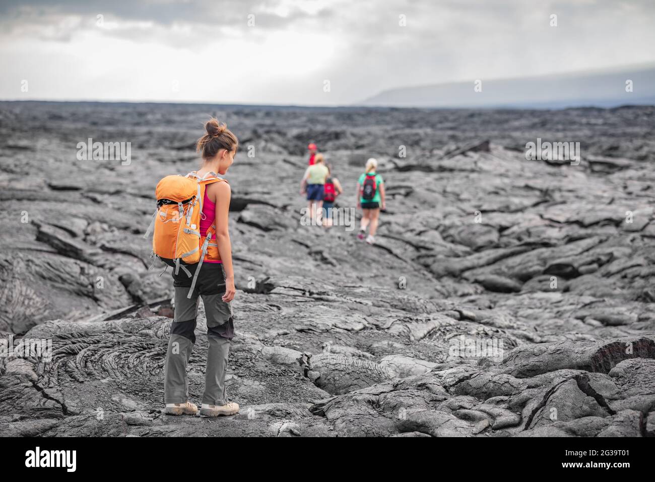 Hiking group of hikers walking on Hawaii volcano lava field hike adventure happy woman with backpack in Big Island, Hawaii. Tourists walking on guided Stock Photo