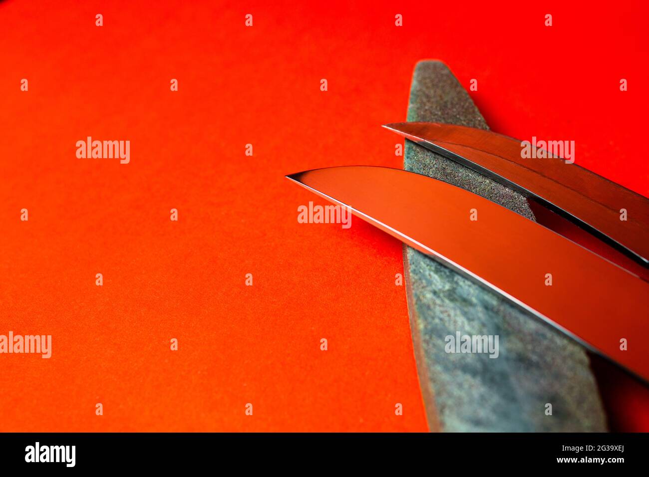knife sharpening and stone for sharpening knives on a red background Stock Photo