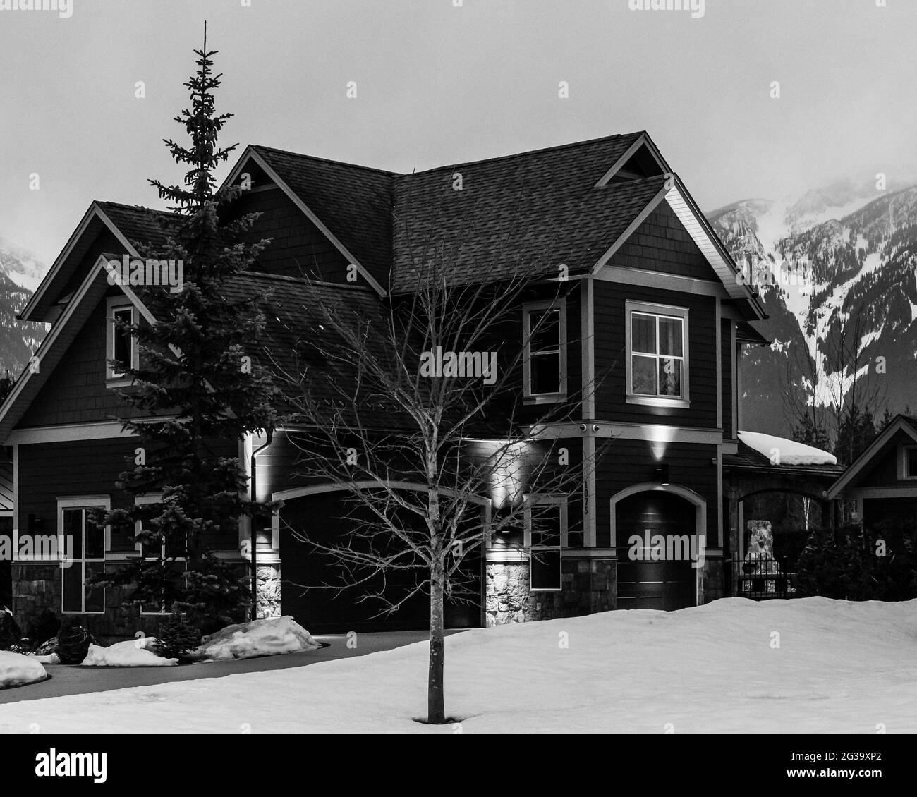 REVELSTOKE, CANADA - MARCH 14, 2021: black and white private home in small town evening time early spring with snow Stock Photo