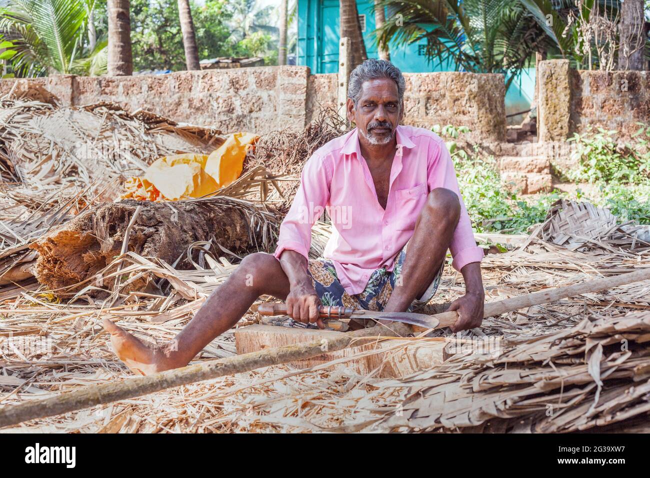 Indian manual worker wearing pink shirt and using machete poses for portrait, Agonda, Goa, India Stock Photo
