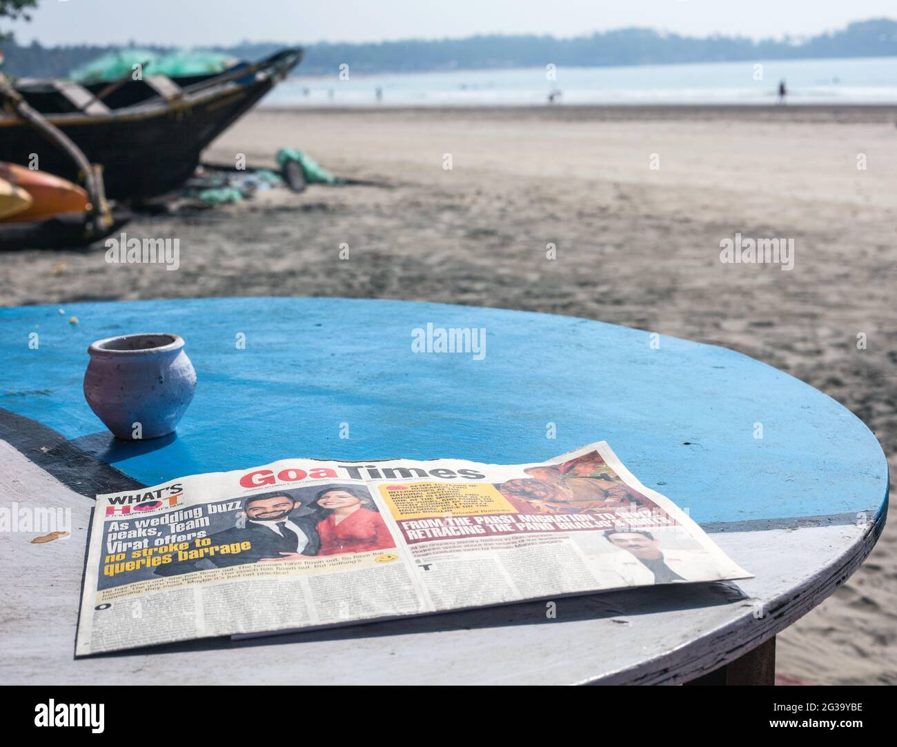 Copy of Goa Times newspaper lying on table in sunlight on Palolem Beach, Goa, India Stock Photo