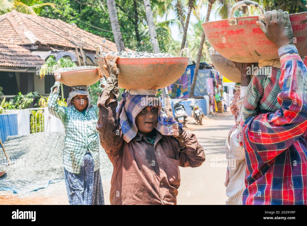 Female Indian manual labour workers carrying heavy loads on their heads at construction site, Agonda, Goa, India Stock Photo