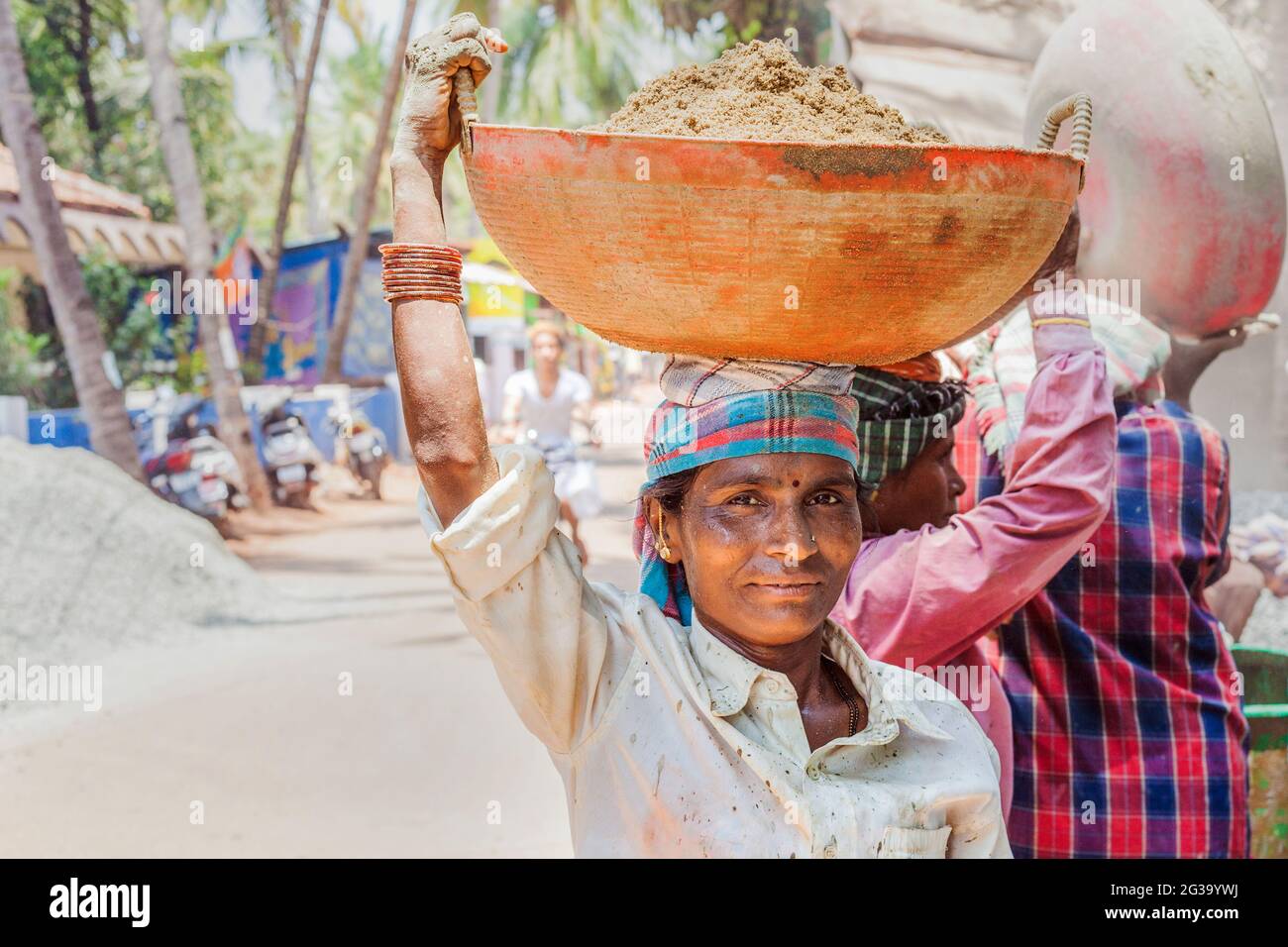 Female Indian manual labour worker carrying heavy load on her head