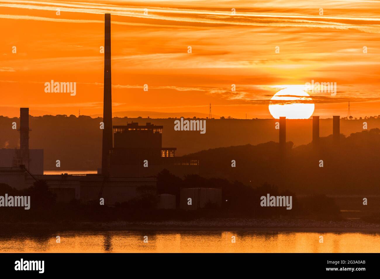 Whitegate, Cork, Ireland. 15th June, 2021.Sunrise  behind the ESB generationg Station in Aghada, Co. Cork, Ireland. - Credit; David Creedon / Alamy Live News Stock Photo