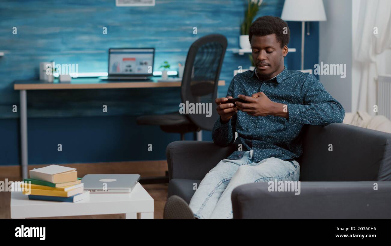 Exhausted african american man falling asleep while holding phone in