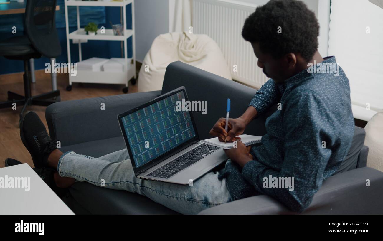 African american man analyzing crypto currency stock markets trading,  checking stock ticker index, deciding to buy