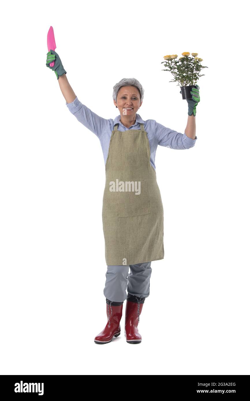Gardening. Mature woman gardener worker with flowers in pot and scoop ...