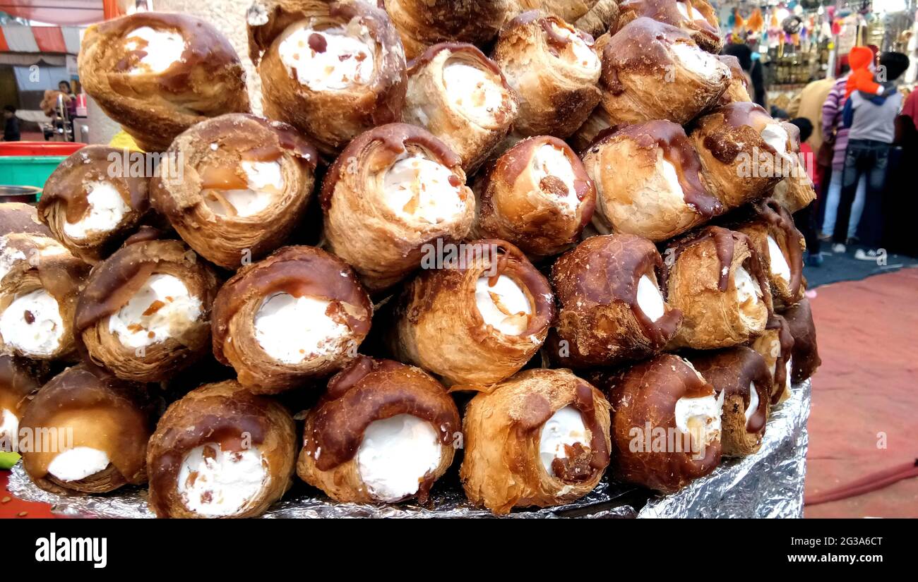 Bunch of puff pastries filled with whipped cream in powder sugar coating sell on indian market Stock Photo