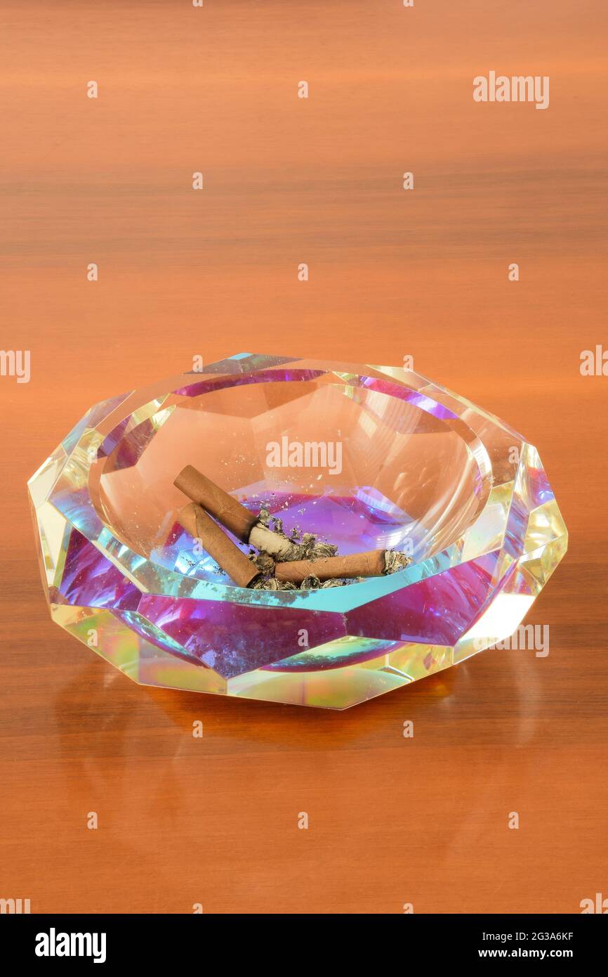 Crystal ashtray with extinct cigars on a wooden table Stock Photo