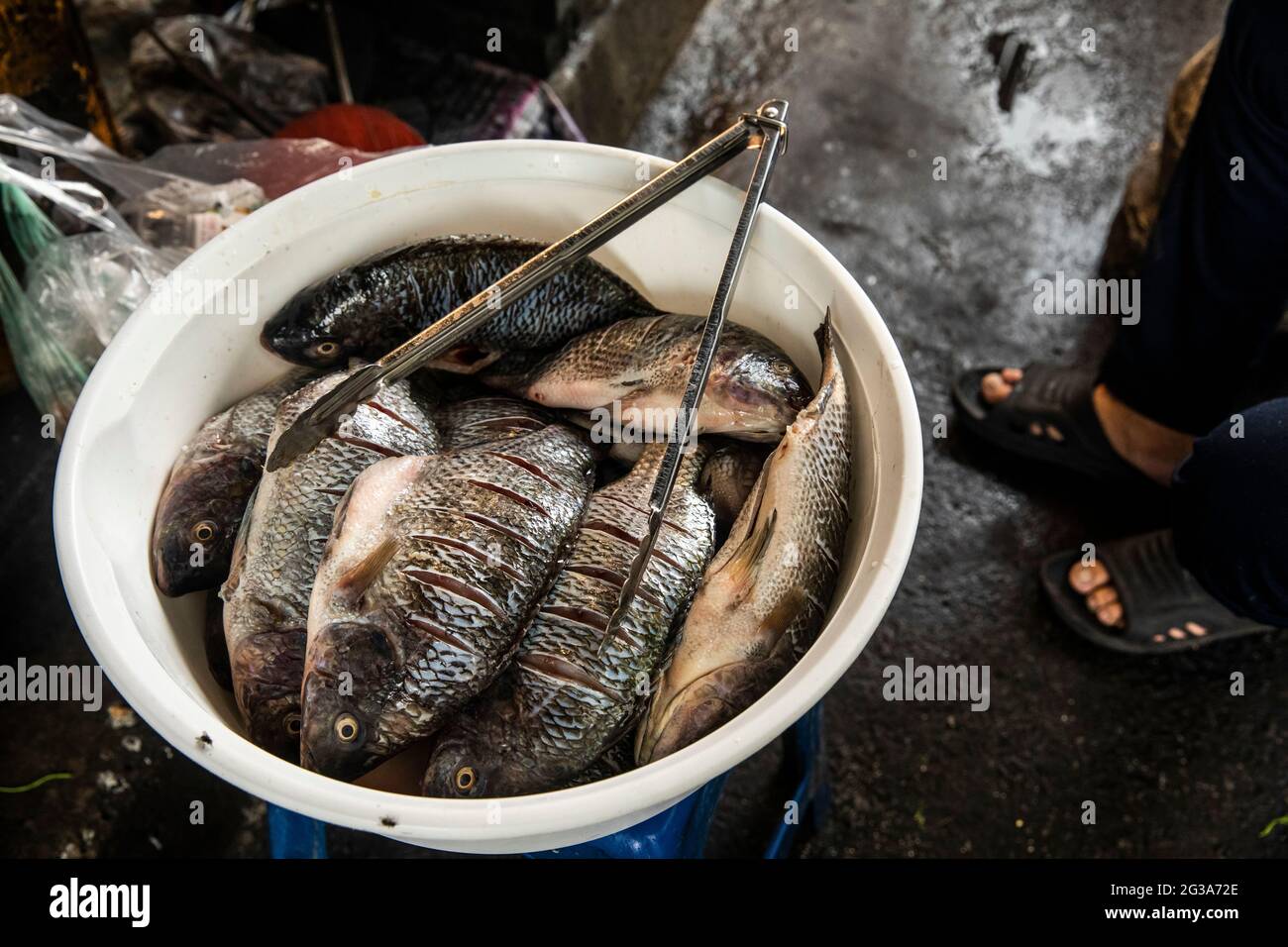 A close-up view of a bowl of whole fish ready to be fried in boiling oil at a Bangkok, Thailand, street food eatery. Stock Photo