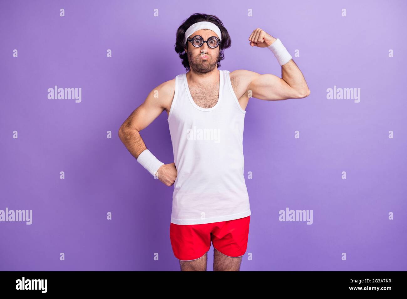 Photo of crazy funny sportsman puffed cheeks demonstrate muscle wear glasses sportswear isolated purple background Stock Photo