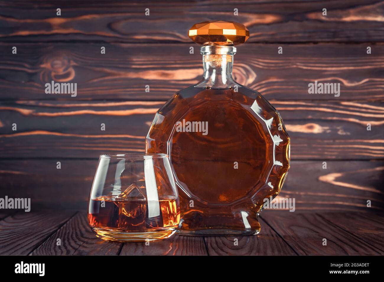 Glass and bottle of whiskey. Decanter with cognac on a dark brown wooden table. Brandy, bourbon. Strong alcohol drink. Rum, scotch. Still life in a ru Stock Photo