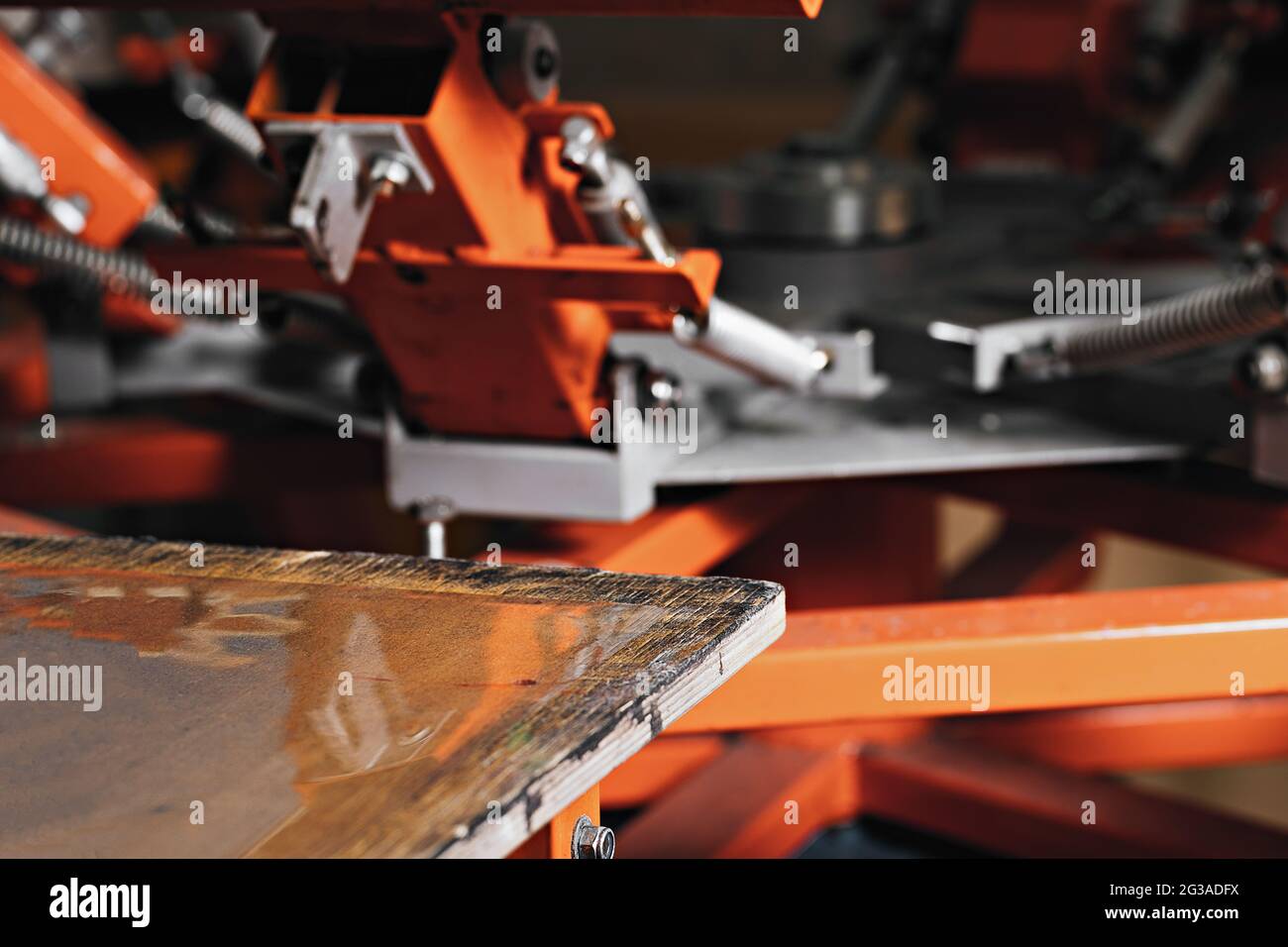 selective focus photo of a wooden shelve of the print screening apparatus. serigraphy production. printing images on t-shirts by silkscreen method in Stock Photo