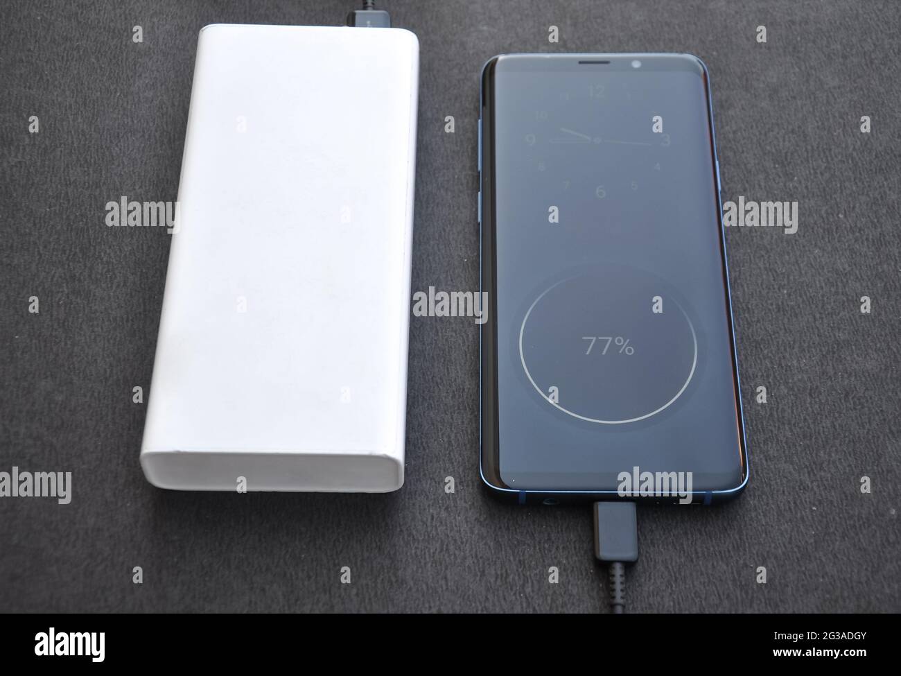 Photo of a black color smartphone connected with power bank for charge ...