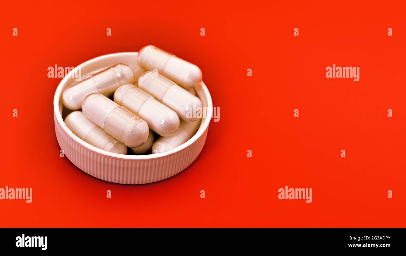 close-up of white capsules on orange background. mental wellbeing and personal health concept Stock Photo