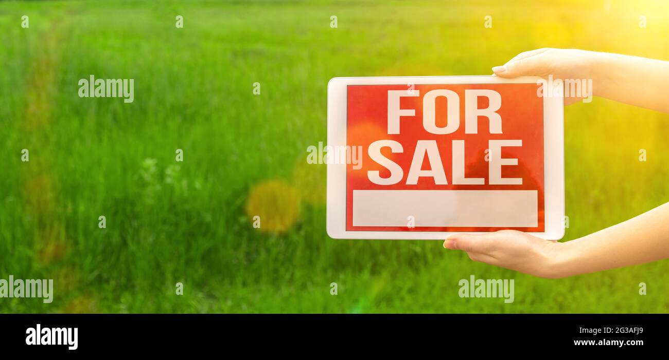 Land for sale banner with sign, tablet with text message in hand