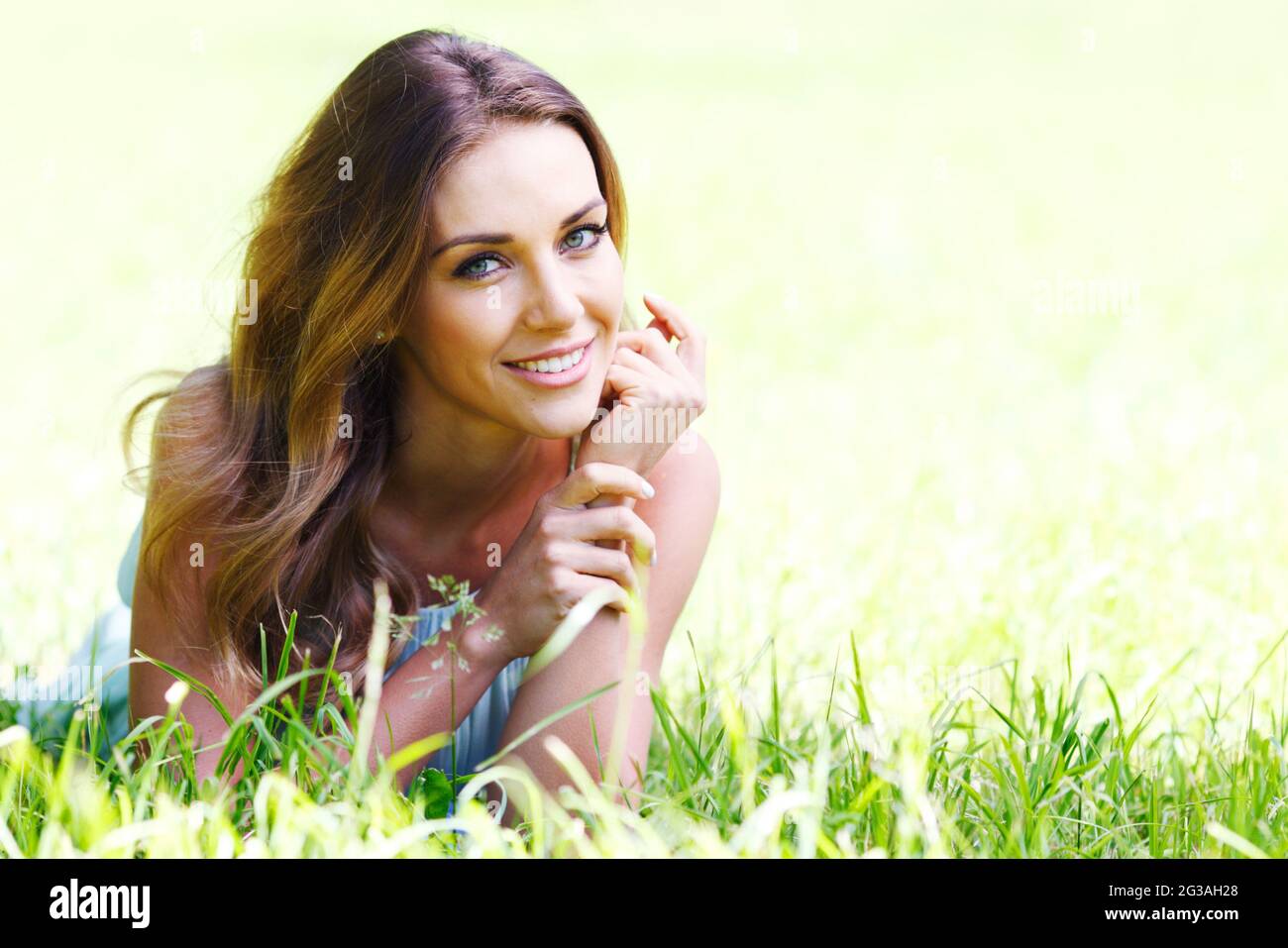 beautiful young woman in blue dress lying on grass Stock Photo - Alamy