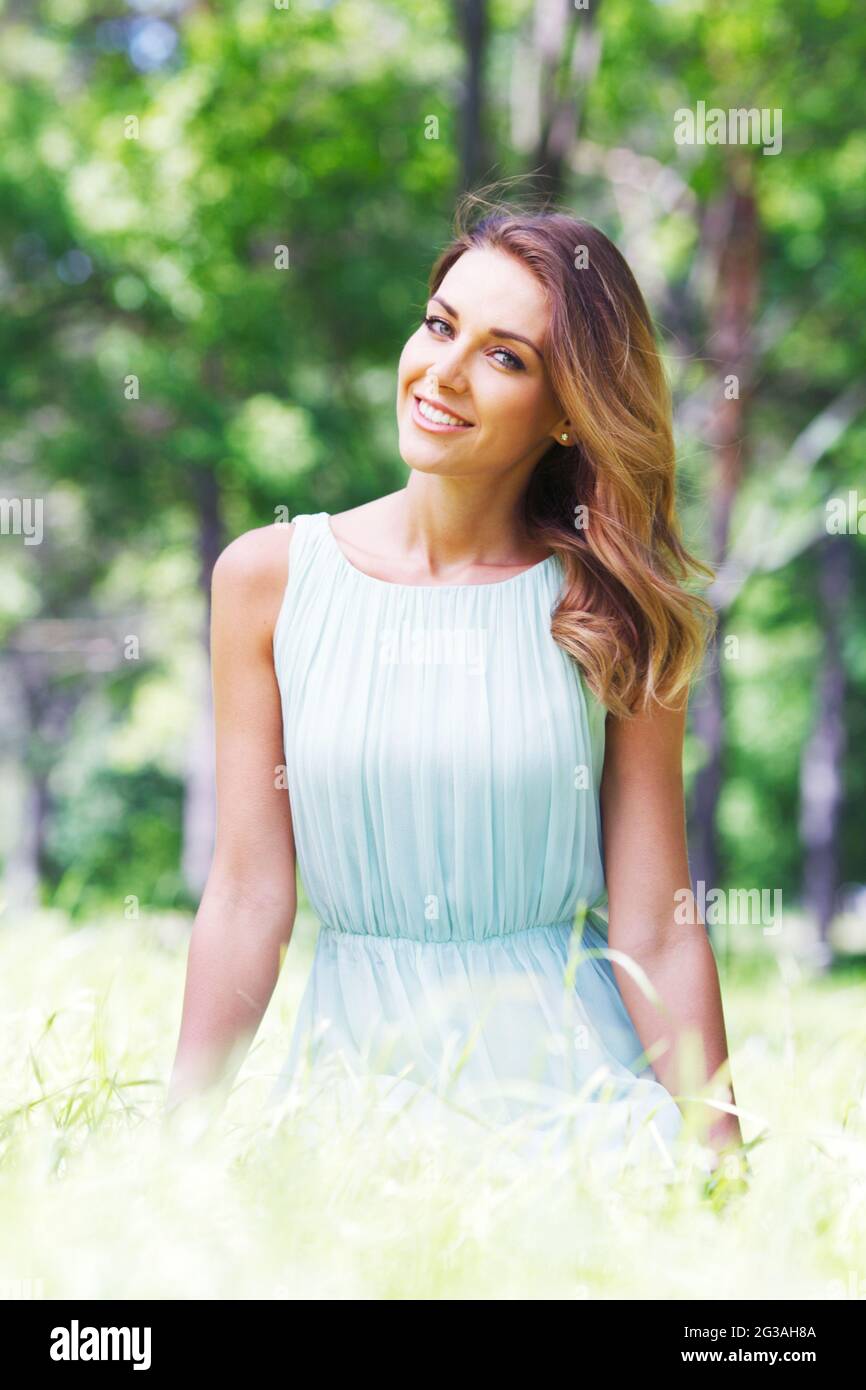 Beautiful young woman in blue dress sitting on grass Stock Photo - Alamy