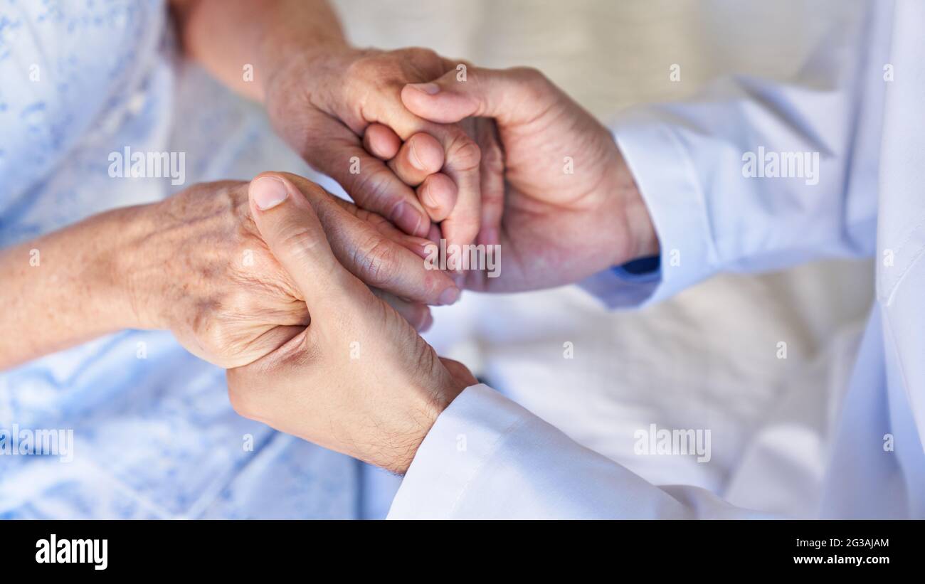 Hands of a senior woman hold in bereavement for comfort and sympathy in the care of the elderly Stock Photo