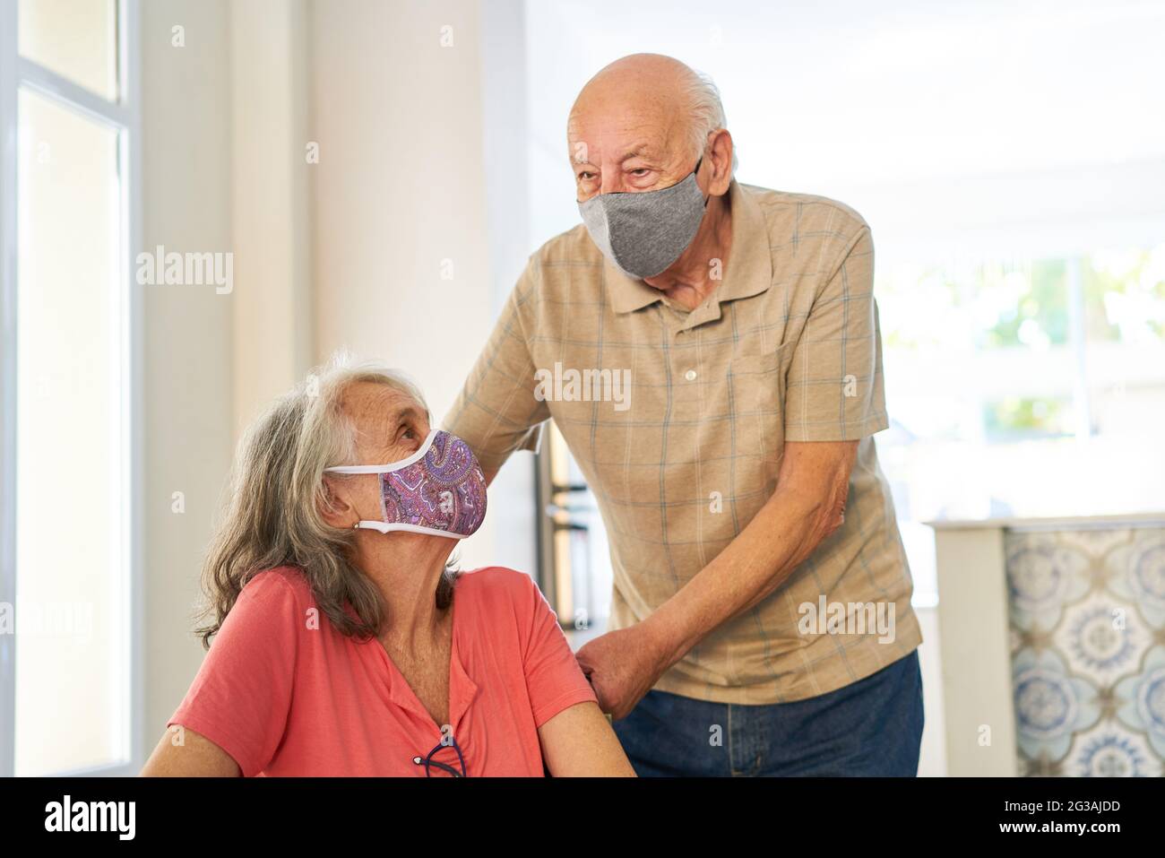 Senior couple with face mask because of Covid-19 and coronavirus as a symbol for vulnerable group Stock Photo