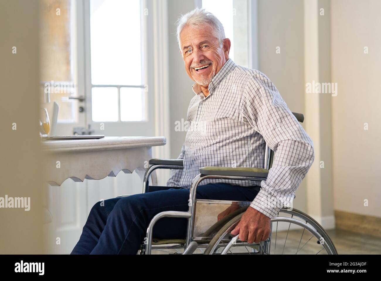 Senior at home sitting in wheelchair after stroke smiling Stock Photo