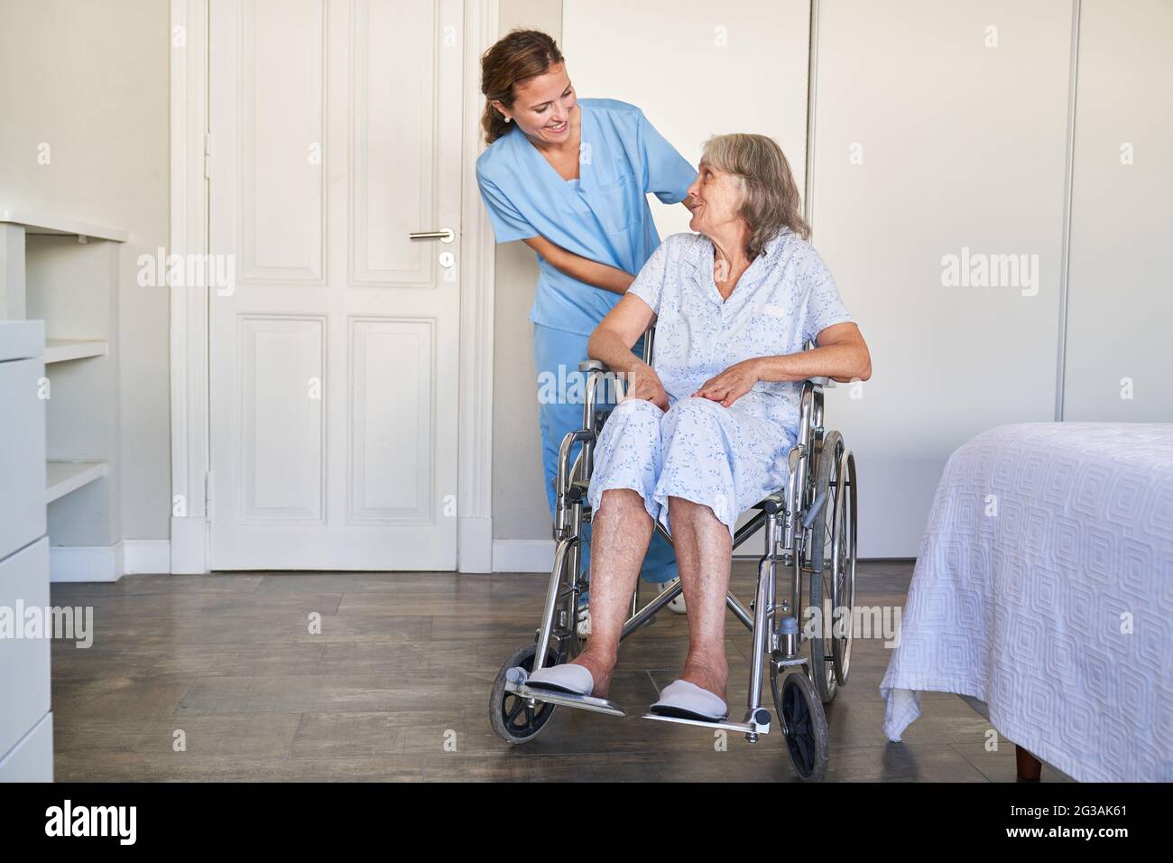 Carer helps elderly woman in a wheelchair after a stroke in hospital or