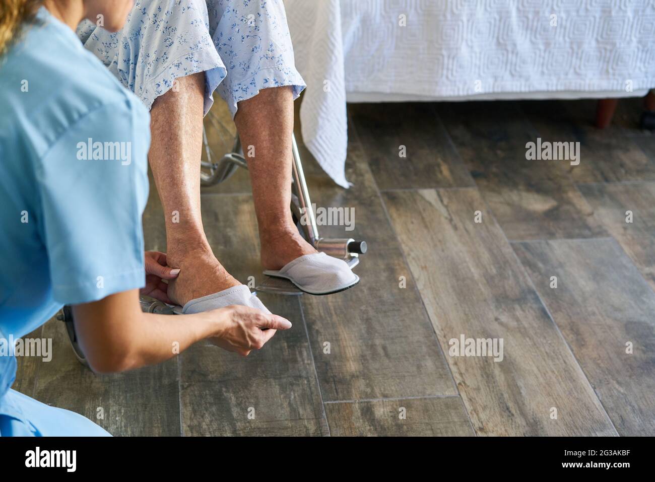 Geriatric nurse helps frail senior citizen in a wheelchair to put on