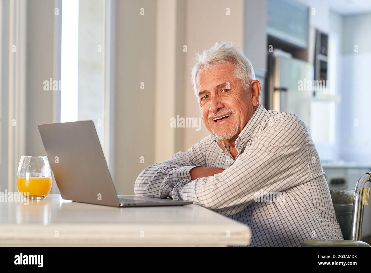 Happy retired senior using laptop computer at home enjoying the internet Stock Photo