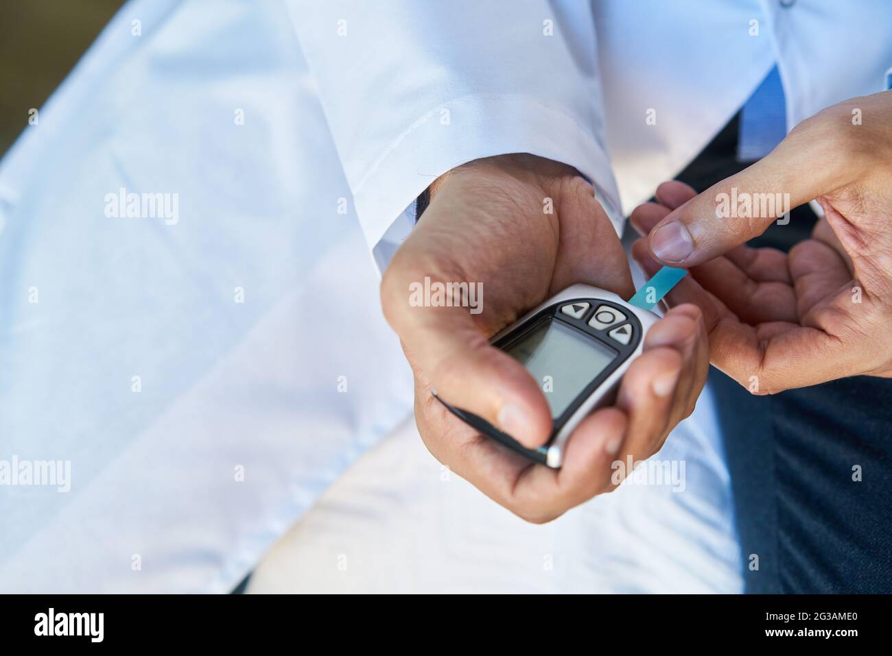 Doctor's hand inserts test strips into the blood glucose meter for diabetes diagnostics Stock Photo