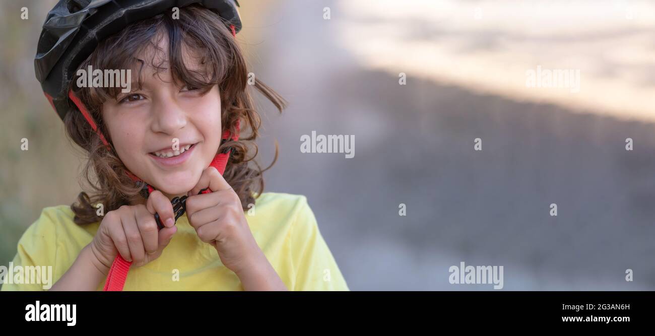 little smiling boy fastens his safety helmet before riding a bike. concept safety, fun, leisure and free time Stock Photo